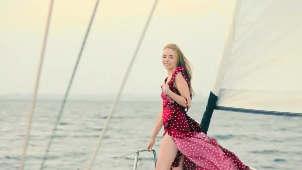 日落时穿着晚礼服的女孩站在游艇上.夜船旅行。穿着雅致衣服的女人在起风.在清澈大海的游艇上快乐的女人 — 图库视频影像