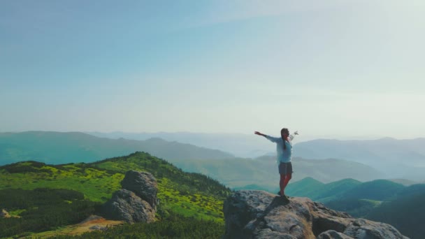 Happy woman standing on a big stone. Beautiful landscape of the Ukrainian Carpathians. Morning in the mountains. Female tourist spins around standing — стокове відео