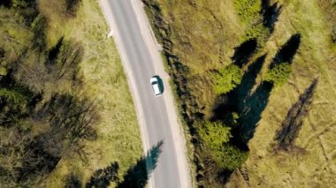 Hava manzaralı araba yolculuğu. Dağlara giden yol. Güneşli bir günde otobanda uçan bir dron ve yeşil Noel ağaçları.