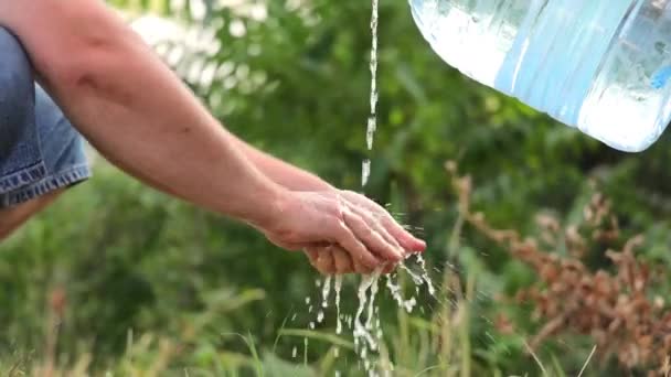 The man washes his hands thoroughly. Water is poured from a plastic bottle into a mans hands. Hand washing. — Stock Video