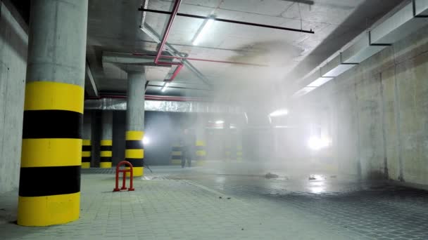地下駐車場での水道管のブレークスルー。駐車場に水が流れている。配管工は漏水を監視してる. — ストック動画