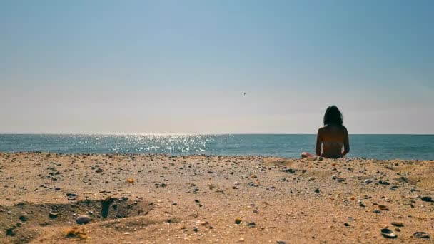 Playa de arena y una mujer mirando a la distancia en el mar. Mirando hacia el futuro. Relájate en la playa. Meditación en la playa. — Vídeos de Stock