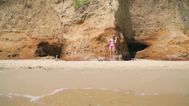 Chica joven y solitaria en la playa en traje de baño corre a nadar. Playa de arena salvaje y una chica en la playa. — Vídeos de Stock