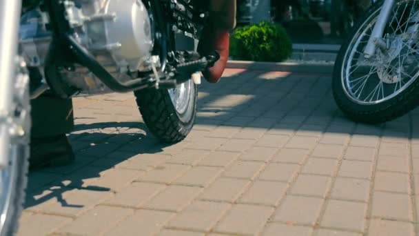 Nogi motocyklisty, który stawia motocykl na stanowisku i wysiada z motocykla. Człowiek, który przyjechał na motocyklu i umieścił go na parkingu.. — Wideo stockowe