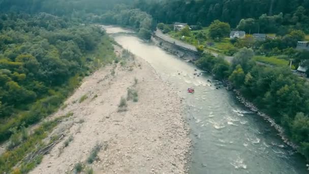 Vista aérea Rafting en barcos en un río de montaña. Un equipo de turistas extremos en cascos en un barco rojo navega en un río tormentoso. — Vídeos de Stock