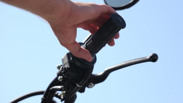 Primer plano de una manopla de mano en el manillar de una motocicleta. Motociclista aprieta el gatillo del gas sobre un fondo de cielo azul. — Vídeos de Stock