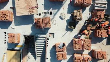 Kırmızı tuğladan bir evin en üstteki hava manzarası. İnşaatçılar çok katlı bir tuğla ev inşa ediyorlar..