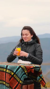 Bir dağ kafeteryasında portakal suyu içen kadın, sonbahar Karpatlar 'ın büyüleyici manzarasına sahip..