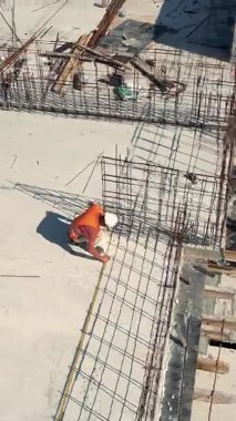 İnşaat işçisi inşaat iskeletini ölçüyor. Güvenlik teçhizatı kullanan bir inşaat işçisi, inşaat halindeki bir binanın beton zemininde çelik demiri takviyesini ölçer..