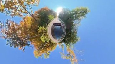 Güzel bir sonbahar döneminde kırsalda yapılan bir yolculuğun 360 manzaralı küçük gezegen manzarası renkli devrilmiş ağaçları ve parlak mavi gökyüzü olan bir arabanın küresel perspektifi..