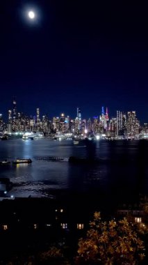 Manhattan siluetinin ay ışığı altında parlaması Hudson Nehri 'ne yansıyor. Iconic Manhattan silueti, Hudson Nehri' ne yansıyan ay ışığıyla hızlandırılmış bir zaman çizgisi.