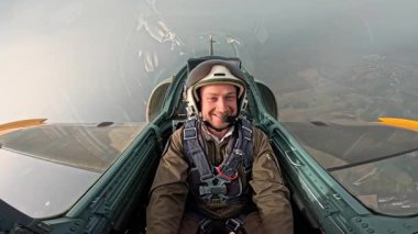 Uçuş sırasında savaş uçağı kokpitinde gülümseyen mutlu askeri pilot, uçakta kask ve uçuş kıyafeti giyen olumlu bir erkek pilot..