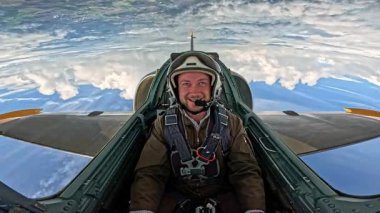 Askeri üniformalı gülümseyen erkek pilot beyaz bulutların üzerinde jet uçağı uçuruyor, açık mavi gökyüzünde uçarken kokpitte pilot portresi çiziyor..
