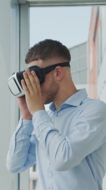 Ofiste masa başında oturan genç adam çeşitli alanlardaki iş projelerinde çalışmak için artırılmış gerçeklik gözlüğü kullanıyor. Sanal Gerçeklik Çalışması.