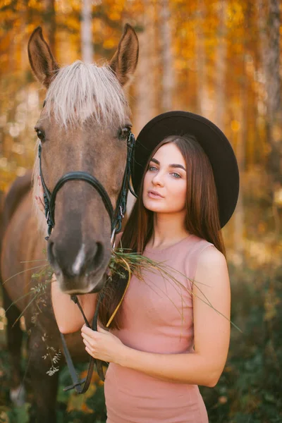 帽子をかぶった女の子は自然の中で馬に座っています — ストック写真