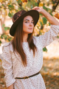 Kız parkta elbisesi ve şapkasıyla yürüyor..