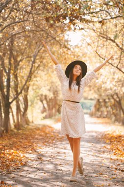 Kız parkta elbisesi ve şapkasıyla yürüyor..