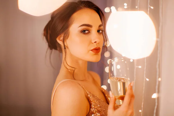 Yeni yıl stüdyosunda elinde bir bardak şampanyayla poz veren gece kıyafetli bir kız.