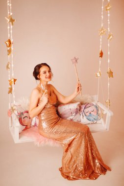 Stüdyoda salıncakta bardakla poz veren bir kız..