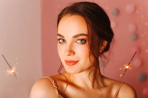 Pembe arka planda maytaplarla poz veren kız.