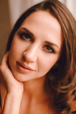 Stüdyoda poz veren yırtık kot pantolon ve siyah sutyen giyen esmer kadın.