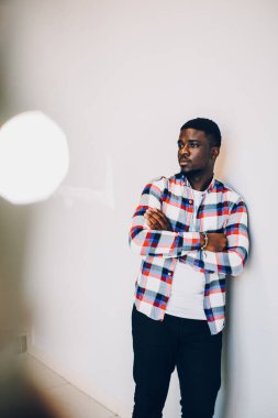 Beyaz arka planda poz veren tişörtlü siyah adam.