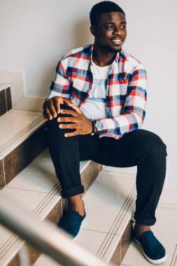 Beyaz arka planda poz veren tişörtlü siyah adam.