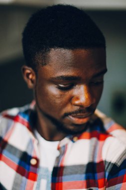 Beyaz arka planda poz veren tişörtlü siyah adam.