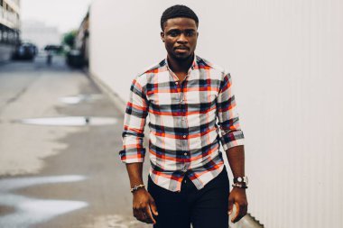 Beyaz arka planda poz veren tişörtlü siyah adam.