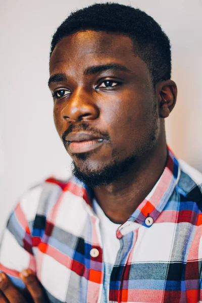 Beyaz arka planda poz veren tişörtlü siyah adam.