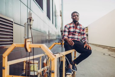 Gömlekli siyah adam sokakta duruyor.