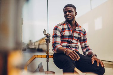 Gömlekli siyah adam sokakta duruyor.