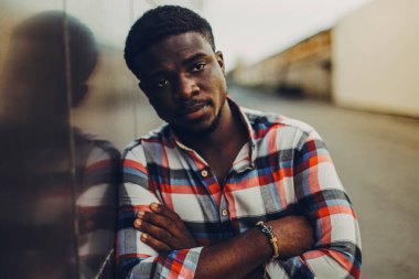 Gömlekli siyah adam sokakta duruyor.