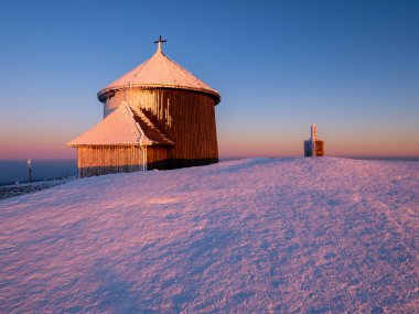 Polonya 'daki Karkonosze Dağları' nda kışın günbatımında Sniezka dağının zirvesinde eski bir şapel.