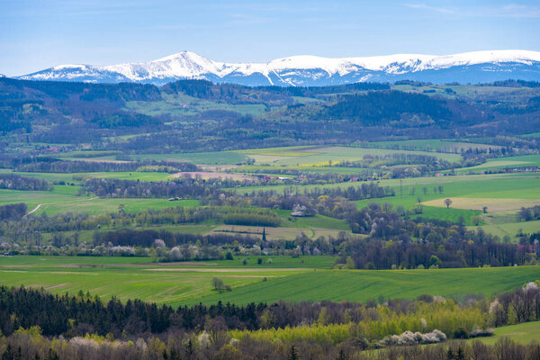 View on Sudety with snowy Karkonosze mountains with green meadows during spring in Poland