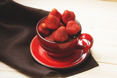 Karanlık bir masa örtüsü üzerinde kırmızı Kupası'nda sulu çilek