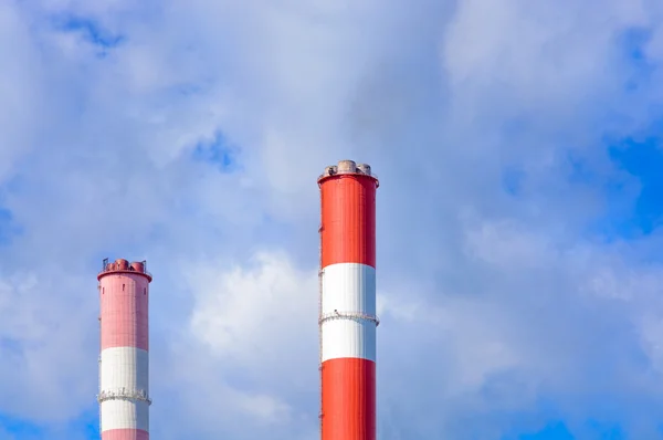 De schoorstenen tegen de blauwe hemel met wolken — Stockfoto