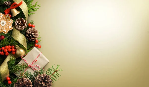 Noel sınır kompozisyonu açık altın arka planda köknar dalları, koniler ve hediye kutusundan yapılmıştır — Stok fotoğraf