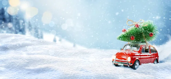 雪の冬の森の屋根の上にクリスマスツリーを運ぶレトロなおもちゃの車。クリスマスの背景。休日カード. — ストック写真