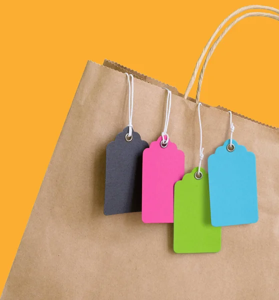 Färgglada prislappar med rep hängande i brun shoppingväska. — Stockfoto