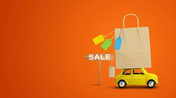 Yellow car with shopping paper bag from a sale on the roof — Stock Photo, Image