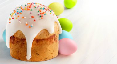 Renkli paskalya yumurtaları ve beyaz ahşap masada Paskalya pastası..