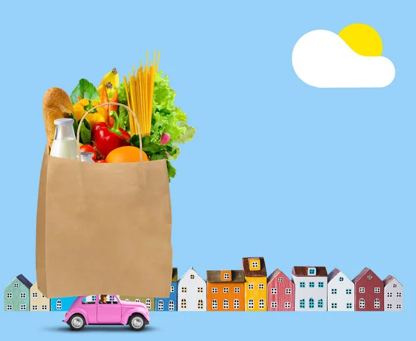 Pink car with shopping paper bag with groceries on the roof on city background — Stock Photo, Image