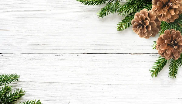 Christmas tree branches and pine cones on white wood background — Stock Photo, Image