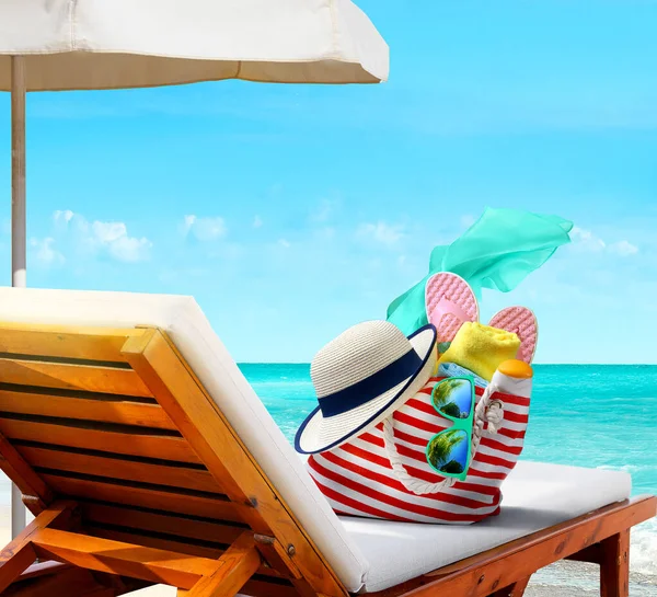 Пляжная сумка с аксессуарами на шезлонге на пляже — стоковое фото