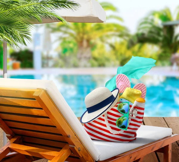 Τσάντα παραλίας με αξεσουάρ στην ξαπλώστρα κοντά στην πισίνα στο πολυτελές θέρετρο — Φωτογραφία Αρχείου
