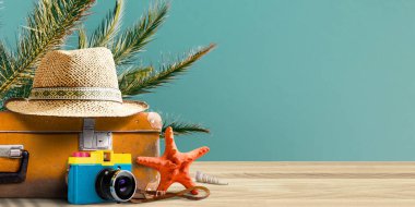 Klasik bavul, retro film kamerası ve deniz manzarası önünde hasır şapka.