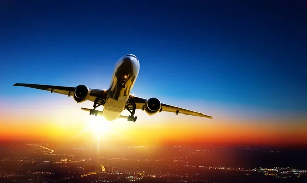 Letadlo odlétá při západu slunce nad městskými světly — Stock fotografie