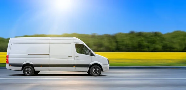 Beyaz minibüs kırsal kesimde asfalt yolda gidiyor..