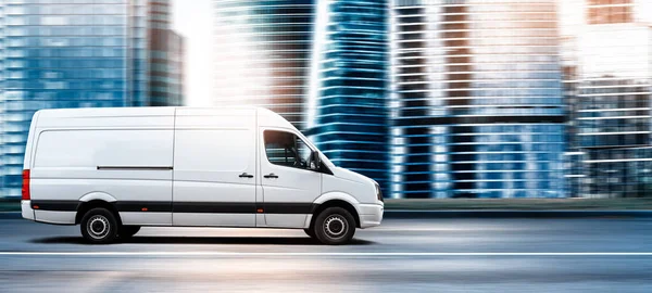 Günbatımında şehir yolunda, modern bir şehrin önünde giden minibüs.